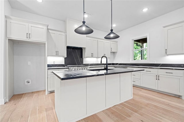1421 Lee St, Pea Ridge, AR 72751 - kitchen with dark countertops, light wood-type flooring, white cabinets, a center island with sink, and recessed lighting