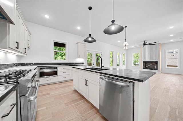 1421 Lee St, Pea Ridge, AR 72751 - kitchen with stainless steel appliances, dark countertops, ceiling fan, recessed lighting, and a large fireplace