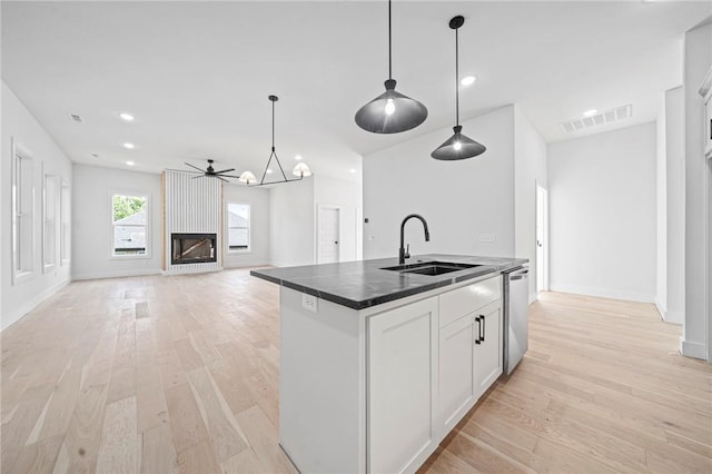 1421 Lee St, Pea Ridge, AR 72751 - kitchen with a sink, dark countertops, dishwasher, a center island with sink, and light wood finished floors