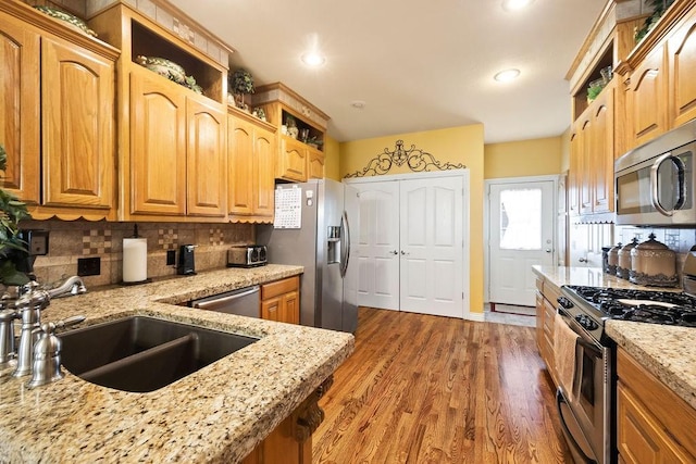 19537 Eastfork Ln, Gravette, AR 72736 - kitchen with appliances with stainless steel finishes, a sink, decorative backsplash, light stone counters, and wood finished floors