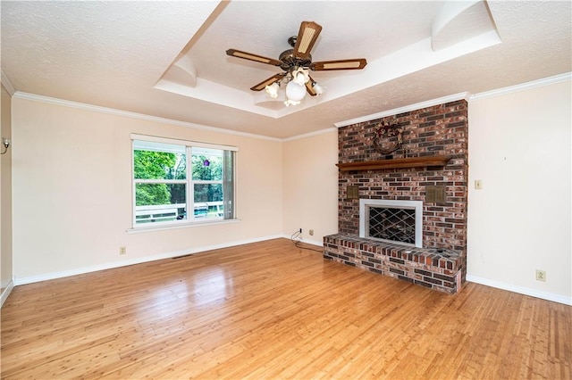 585 County Road 217, Berryville, AR 72616 - unfurnished living room with wood finished floors, a tray ceiling, a brick fireplace, a textured ceiling, and ceiling fan