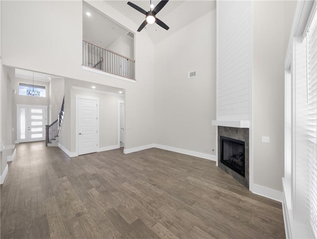 1821 Bluestem Dr, Centerton, AR 72719 - unfurnished living room with a ceiling fan, dark wood-type flooring, a tile fireplace, baseboards, and a towering ceiling