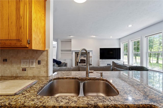 4 Hillcrest Dr, Holiday Island, AR 72631 - kitchen featuring a sink, light stone countertops, open floor plan, decorative backsplash, and brown cabinets