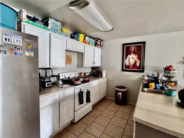 1297 Homestead Loop, Springdale, AR 72764 - kitchen with white range with electric stovetop, freestanding refrigerator, a textured ceiling, white cabinets, and light countertops