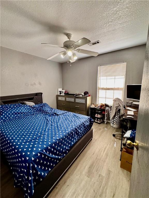 1269 E Homestead Loop, Springdale, AR 72764 - bedroom featuring wood finished floors, a textured ceiling, and a ceiling fan