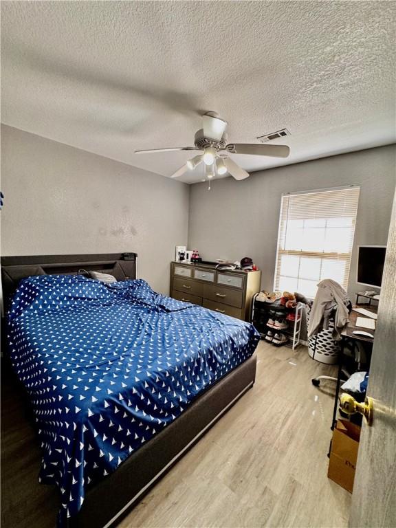 1269 E Homestead Loop, Springdale, AR 72764 - bedroom featuring wood finished floors, a textured ceiling, and ceiling fan