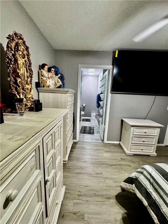1269 E Homestead Loop, Springdale, AR 72764 - bedroom with a textured ceiling, light wood finished floors, and connected bathroom