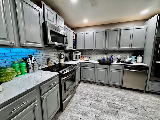 1269 E Homestead Loop, Springdale, AR 72764 - kitchen with stainless steel appliances, gray cabinets, tasteful backsplash, and light countertops