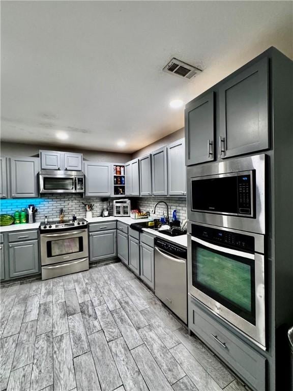 1269 E Homestead Loop, Springdale, AR 72764 - kitchen featuring stainless steel appliances, gray cabinetry, tasteful backsplash, and light countertops