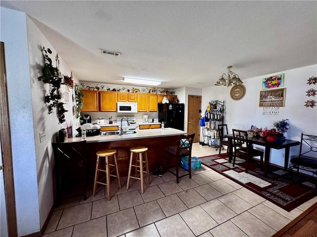 1269 E Homestead Loop, Springdale, AR 72764 - kitchen with white appliances, a peninsula, a chandelier, a kitchen breakfast bar, and light tile patterned floors