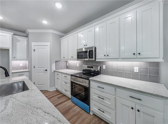 9 Sheidaig Ln, Bella Vista, AR 72715 - kitchen with stainless steel appliances, wood finished floors, white cabinetry, backsplash, and ornamental molding