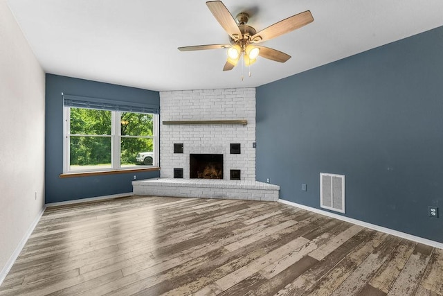 10 Magrath Ln, Bella Vista, AR 72715 - unfurnished living room with a ceiling fan, wood finished floors, baseboards, and a brick fireplace