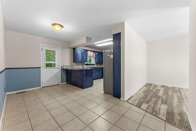 10 Magrath Ln, Bella Vista, AR 72715 - kitchen featuring blue cabinetry, a peninsula, a kitchen bar, dark countertops, and baseboards