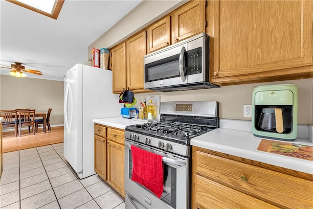 802 Buford St, Springdale, AR 72762 - kitchen featuring appliances with stainless steel finishes, light countertops, ceiling fan, light tile patterned floors, and brown cabinets