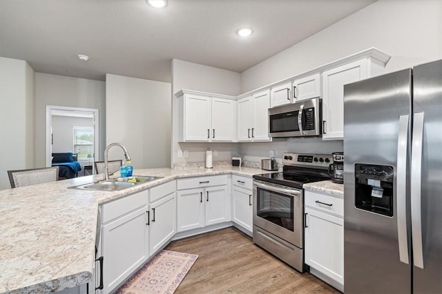 2213 E Fennec St, Siloam Springs, AR 72761 - kitchen with stainless steel appliances, a sink, white cabinetry, light wood finished floors, and a peninsula