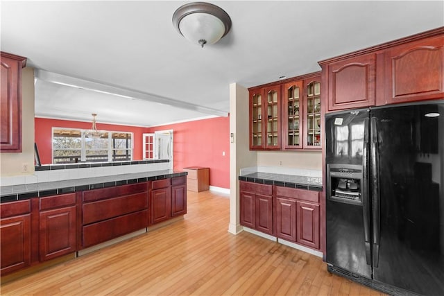 11021 Lathams Landing Rd, Garfield, AR 72732 - kitchen with black fridge with ice dispenser, glass insert cabinets, light wood-style flooring, baseboards, and reddish brown cabinets