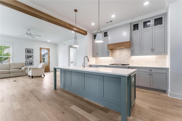 6741 Garden Trail Ave, Springdale, AR 72762 - kitchen featuring gray cabinetry, light countertops, tasteful backsplash, a center island with sink, and light wood-type flooring