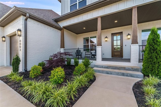 8003 W Claverton St, Rogers, AR 72758 - view of exterior entry featuring brick siding, covered porch, a garage, and a shingled roof