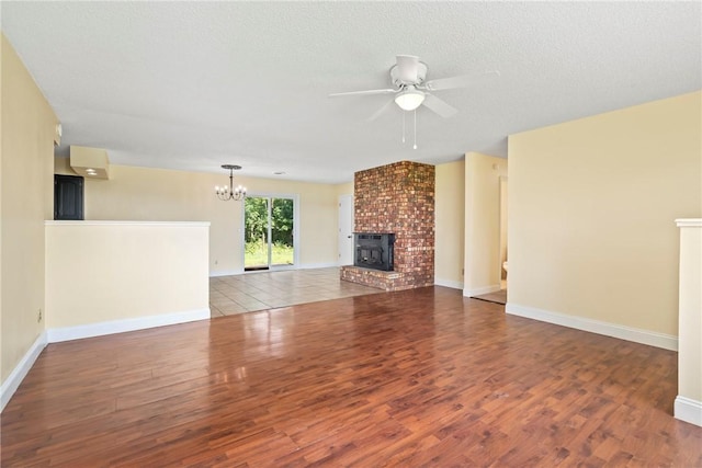 50233 S 725th Rd, Colcord, OK 74338 - unfurnished living room with a chandelier, wood finished floors, a ceiling fan, a fireplace, and a textured ceiling