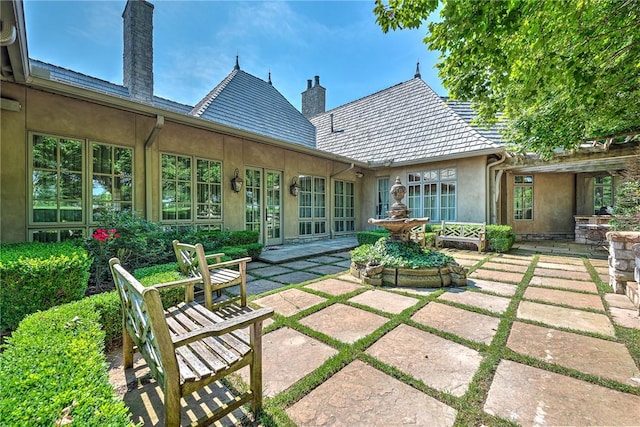 31 W Champions Blvd, Rogers, AR 72758 - back of house featuring a chimney, stucco siding, and a patio