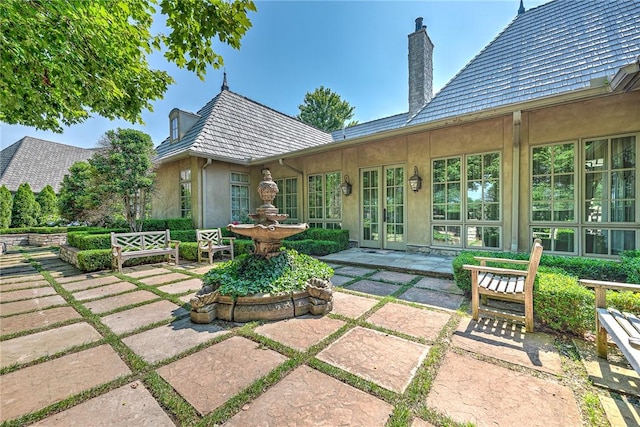 31 W Champions Blvd, Rogers, AR 72758 - back of house featuring stucco siding, a patio area, and a chimney