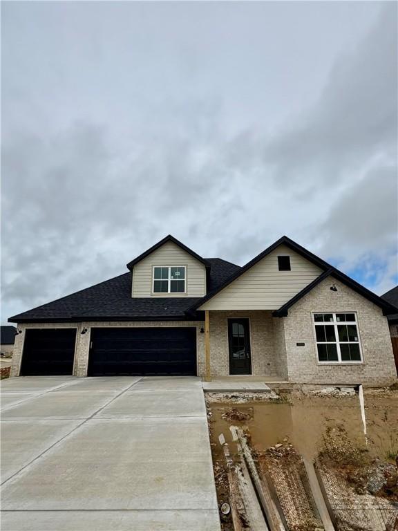 1309 Carrara, Tontitown, AR 72762 - view of front facade with concrete driveway, roof with shingles, and a garage