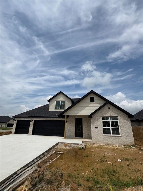 1309 Carrara, Tontitown, AR 72762 - view of front facade with concrete driveway, an attached garage, and roof with shingles