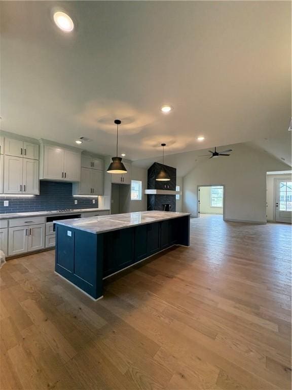 1309 Carrara, Tontitown, AR 72762 - kitchen featuring a kitchen island, light wood finished floors, tasteful backsplash, vaulted ceiling, and recessed lighting