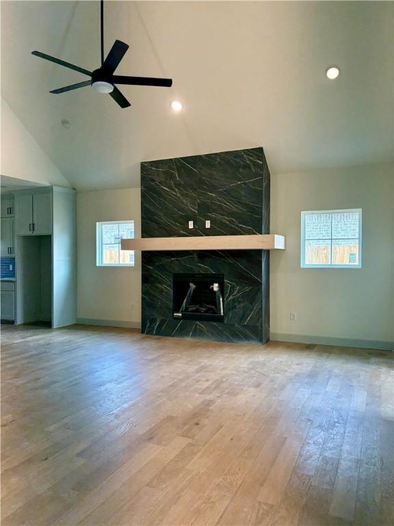 1309 Carrara, Tontitown, AR 72762 - unfurnished living room with lofted ceiling, wood finished floors, a high end fireplace, a ceiling fan, and recessed lighting