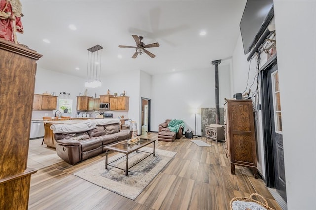19959 Rheas Community Rd, Lincoln, AR 72744 - living area featuring a wood stove, a ceiling fan, recessed lighting, vaulted ceiling, and light wood-style floors