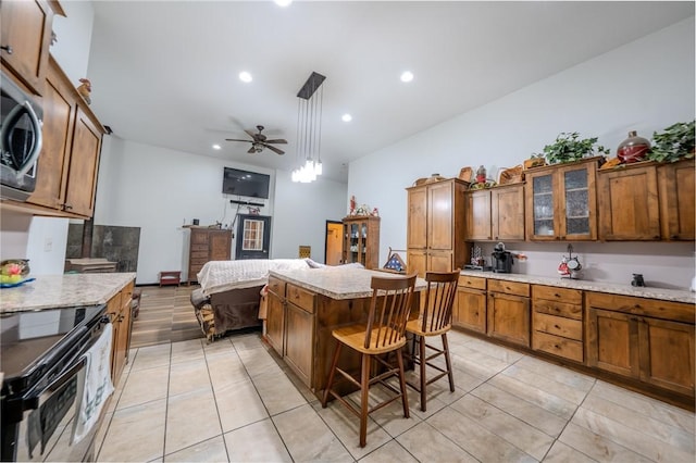 19959 Rheas Community Rd, Lincoln, AR 72744 - kitchen with stainless steel electric range, brown cabinets, ceiling fan, a center island, and a kitchen bar