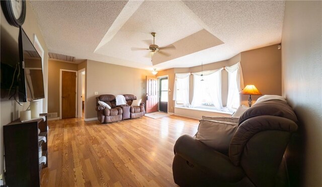 5 Coatbridge Ln, Bella Vista, AR 72715 - living room featuring a textured ceiling, ceiling fan, a raised ceiling, and light wood finished floors