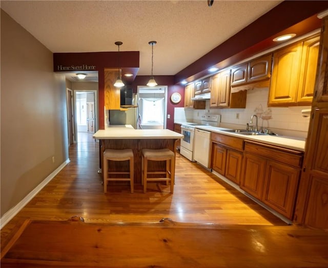 5 Coatbridge Ln, Bella Vista, AR 72715 - kitchen featuring white appliances, under cabinet range hood, a textured ceiling, a breakfast bar area, and light wood finished floors