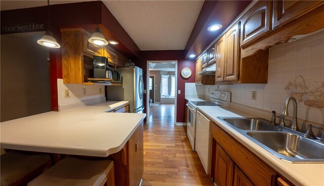 5 Coatbridge Ln, Bella Vista, AR 72715 - kitchen featuring light countertops, under cabinet range hood, decorative backsplash, light wood-type flooring, and a breakfast bar area