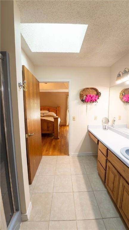 5 Coatbridge Ln, Bella Vista, AR 72715 - bathroom featuring a skylight, vanity, a textured ceiling, and tile patterned floors