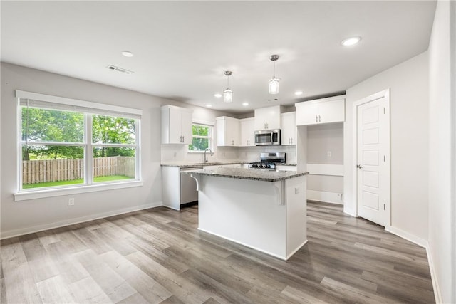 106 N Lion Dr, Gravette, AR 72736 - kitchen featuring stainless steel appliances, white cabinets, light stone counters, wood finished floors, and a kitchen island