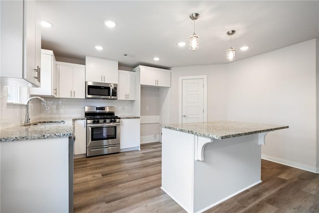 106 N Lion Dr, Gravette, AR 72736 - kitchen featuring appliances with stainless steel finishes, wood finished floors, white cabinets, decorative backsplash, and light stone counters