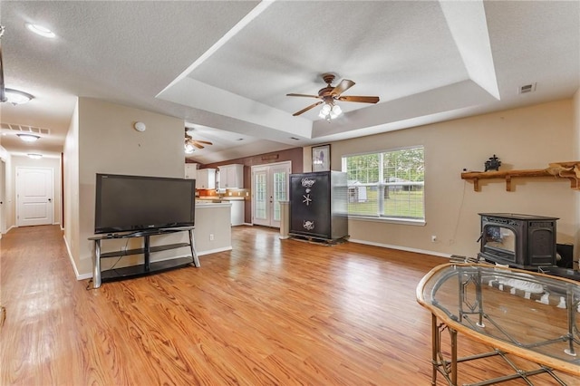 22006 Bozarth Cemetery Rd, Gentry, AR 72734 - living area featuring ceiling fan, a tray ceiling, a wood stove, light wood finished floors, and a textured ceiling