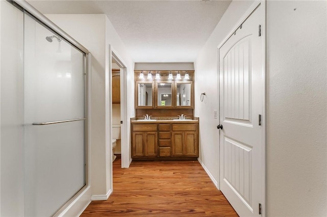 22006 Bozarth Cemetery Rd, Gentry, AR 72734 - bathroom featuring double vanity, wood finished floors, and a stall shower