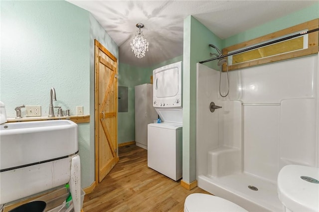 22006 Bozarth Cemetery Rd, Gentry, AR 72734 - bathroom with stacked washing machine and dryer, wood finished floors, a shower, electric panel, and a textured wall