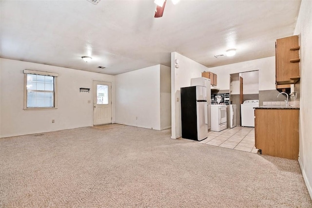 20724 E 578th Rd, Colcord, OK 74338 - kitchen featuring freestanding refrigerator, independent washer and dryer, light carpet, open floor plan, and ceiling fan