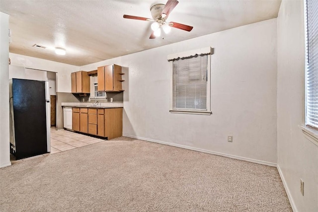 20724 E 578th Rd, Colcord, OK 74338 - kitchen with light carpet, freestanding refrigerator, ceiling fan, dishwasher, and brown cabinetry