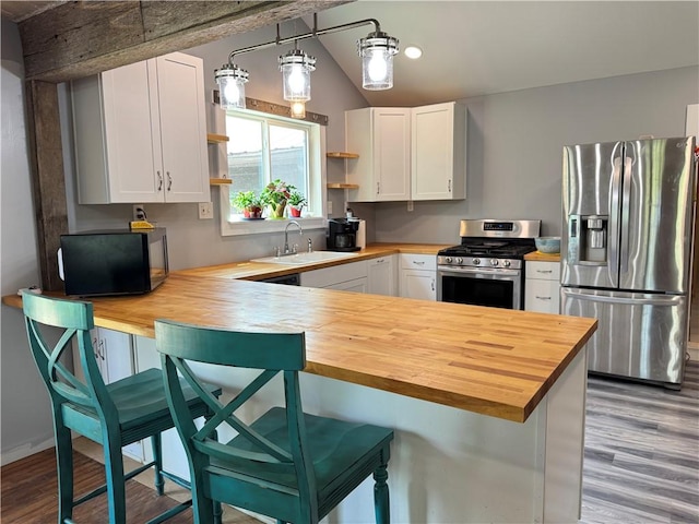 7792 Bubbling Springs Rd, Harrison, AR 72601 - kitchen with wooden counters, stainless steel appliances, open shelves, wood finished floors, and vaulted ceiling