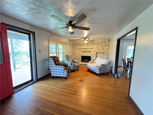 7792 Bubbling Springs Rd, Harrison, AR 72601 - living area featuring ceiling fan, hardwood / wood-style flooring, a stone fireplace, and a textured ceiling