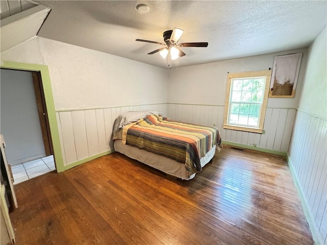7792 Bubbling Springs Rd, Harrison, AR 72601 - bedroom featuring hardwood / wood-style flooring, a textured ceiling, a wainscoted wall, and ceiling fan