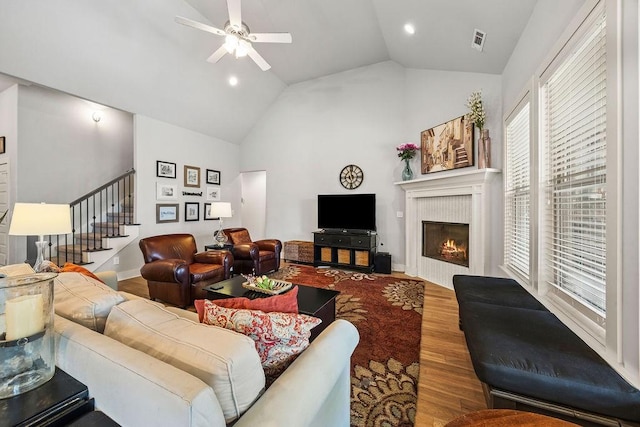 4609 W Waters Edge Dr, Rogers, AR 72758 - living area with wood finished floors, stairway, a ceiling fan, vaulted ceiling, and a lit fireplace