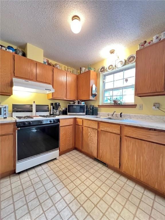 107 Jay Ln, Eureka Springs, AR 72632 - kitchen featuring white range with gas stovetop, under cabinet range hood, stainless steel microwave, light countertops, and a textured ceiling