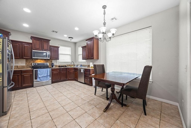 1902 SW Sequoia St, Bentonville, AR 72713 - kitchen with appliances with stainless steel finishes, a chandelier, light tile patterned floors, light countertops, and backsplash