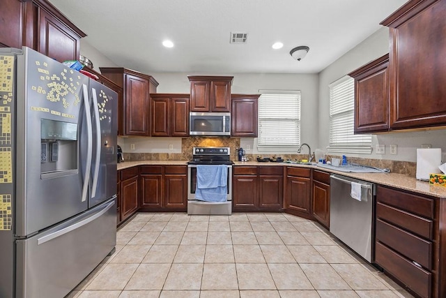 1902 SW Sequoia St, Bentonville, AR 72713 - kitchen featuring stainless steel appliances, light countertops, decorative backsplash, light tile patterned floors, and recessed lighting
