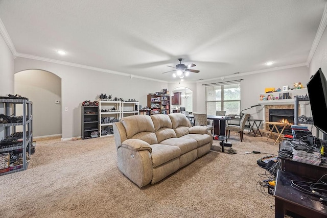 1902 SW Sequoia St, Bentonville, AR 72713 - carpeted living room featuring arched walkways, a ceiling fan, a fireplace, ornamental molding, and recessed lighting